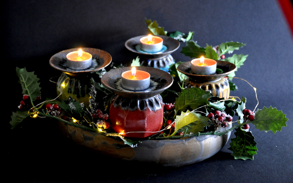 Ceramic poppy seed heads as part of a Christmas wreath with tealight candles on top