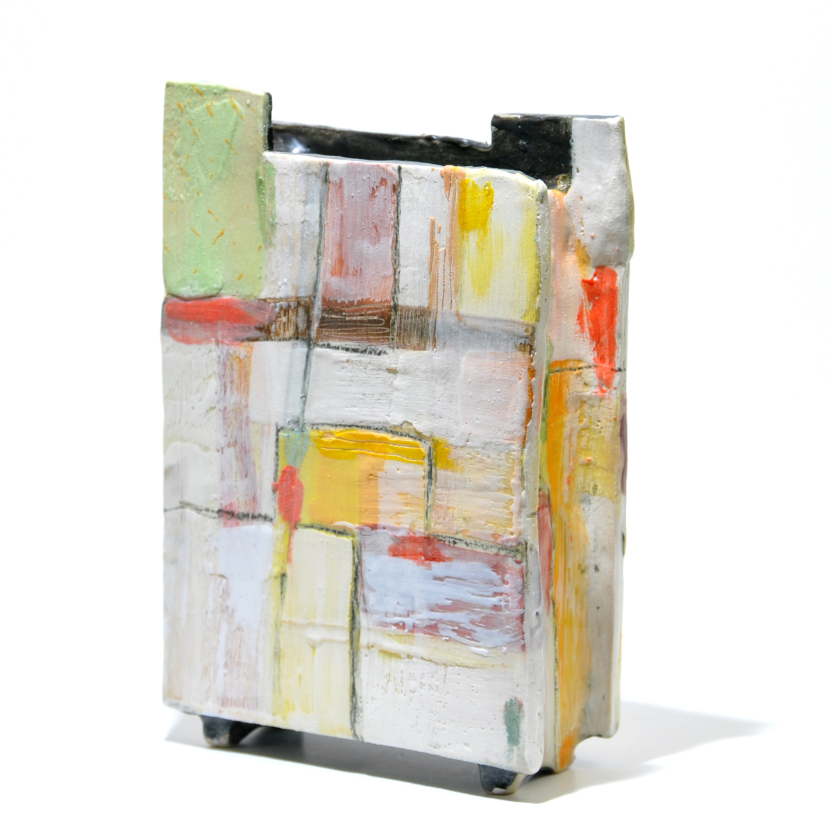 sideways view of rectangular, engobe decorated slab built vase, decorated with white, yellow, umber and orange engobes, wax crayons, pencils and inks