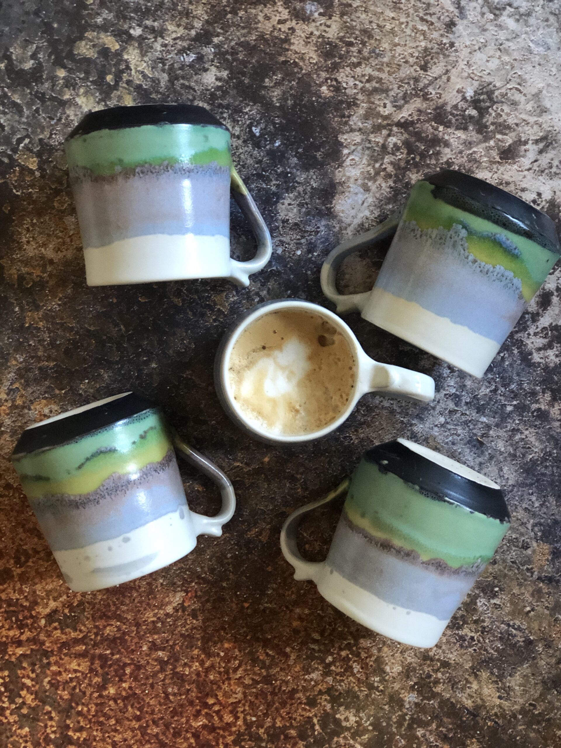 Small mugs in Horizon design, glazed in pastel range of glazes from dark-green to lime-green and light-blue, topped by satin white