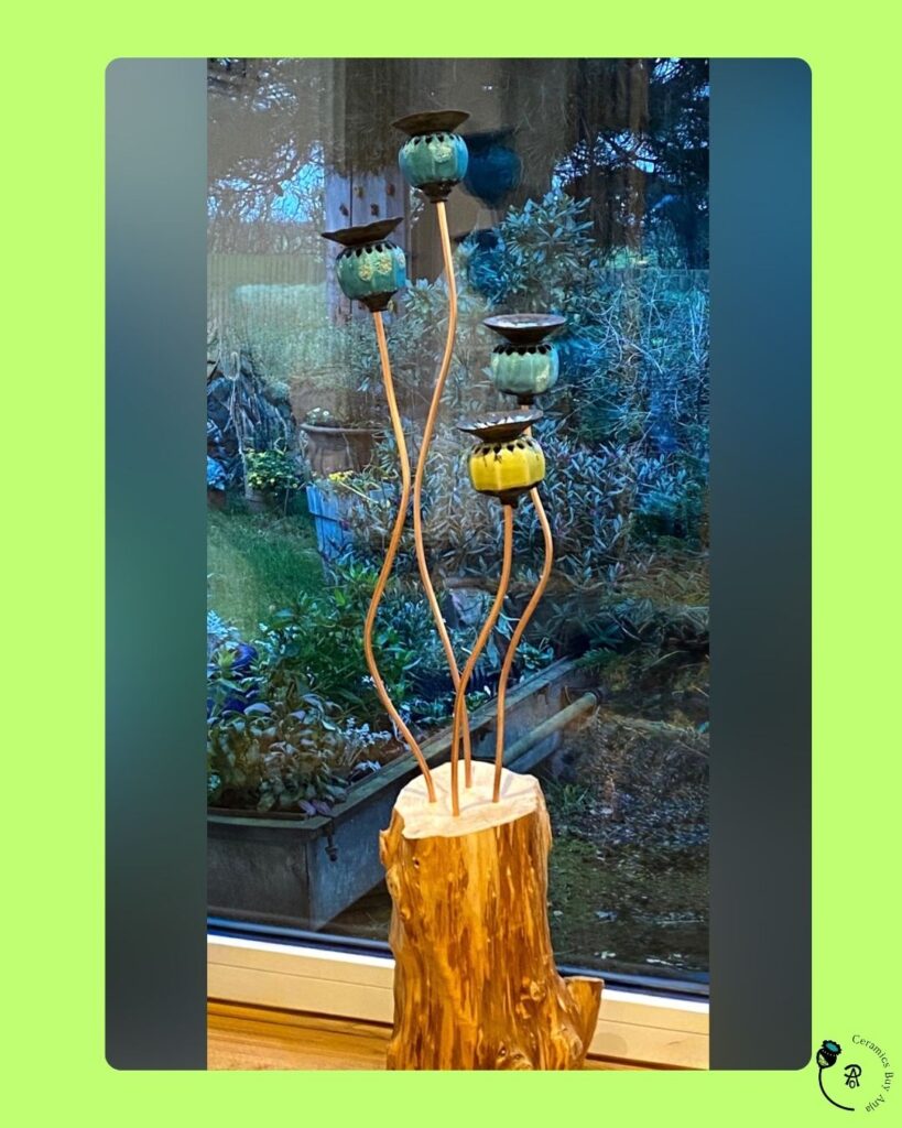 Ceramic poppy seed heads arranged at different heights in a wooden log on the window sill